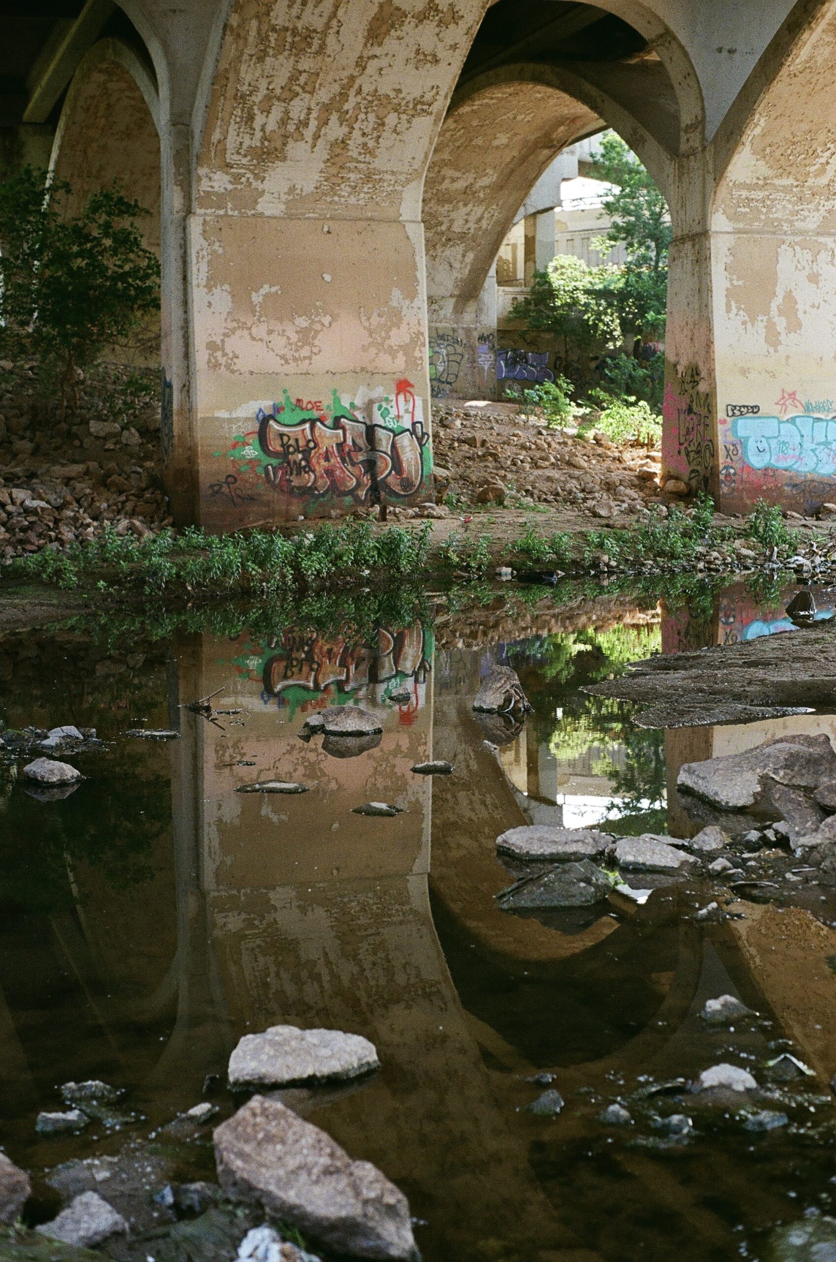 A concrete archway reflected in a pool of still water.